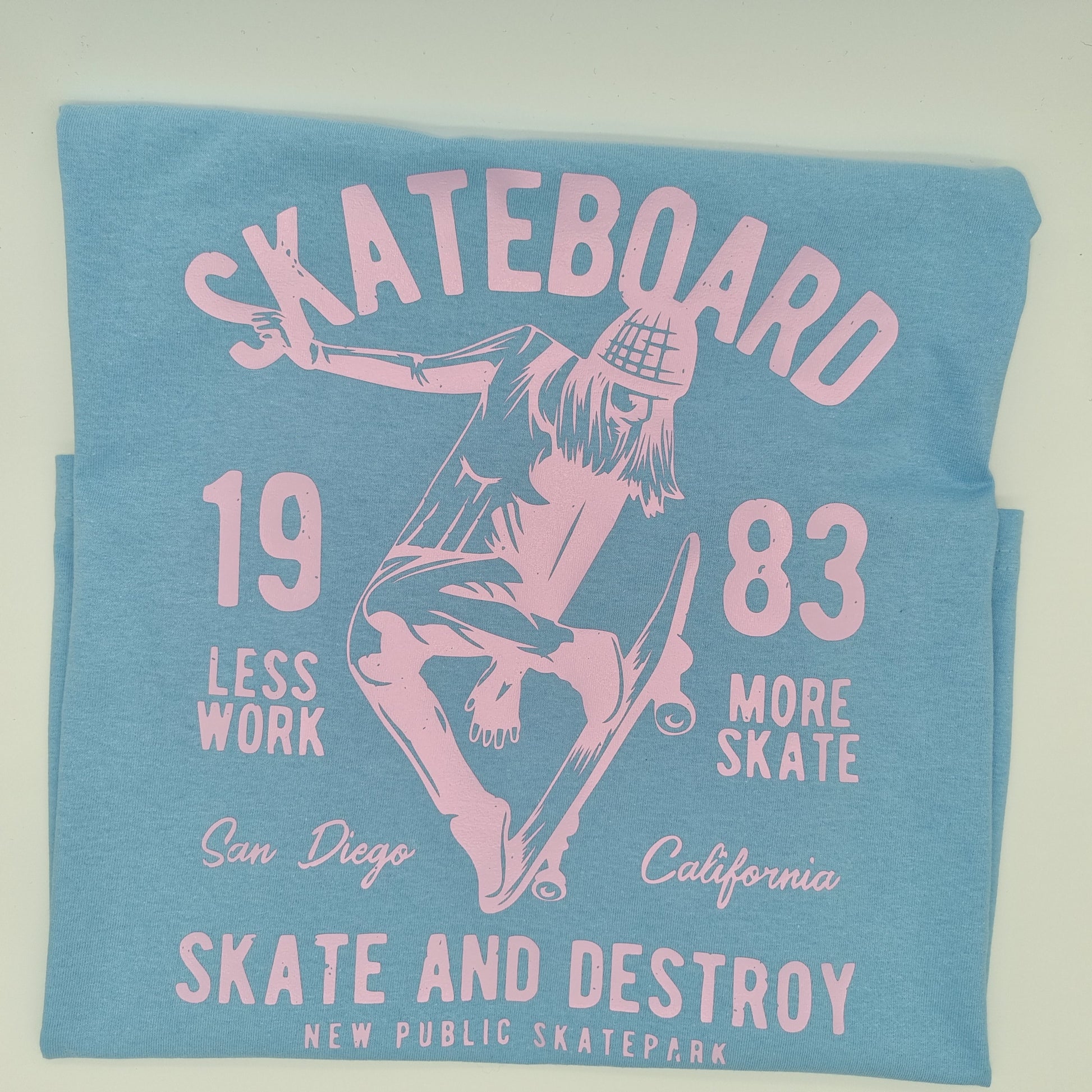 Blue t-shirt with a pink graphic of a girl skating